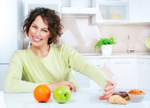 Dieting concept. Young Woman choosing between Fruits and Sweets