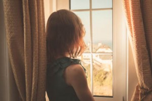 Young woman in dress looking out the window